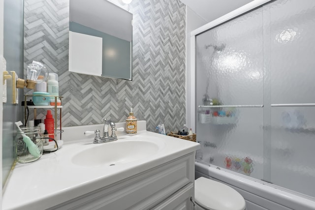 full bathroom featuring combined bath / shower with glass door, vanity, and toilet