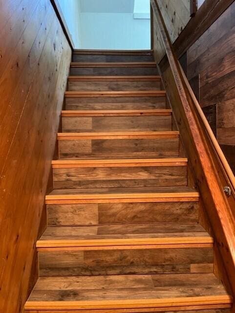 staircase featuring wooden walls