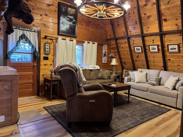 living room featuring wood walls, a high ceiling, hardwood / wood-style flooring, and a notable chandelier