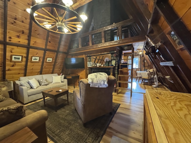 living room featuring hardwood / wood-style floors, lofted ceiling, wooden walls, and a notable chandelier