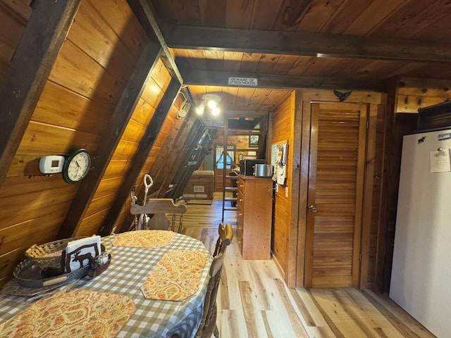 interior space with vaulted ceiling with beams, light hardwood / wood-style floors, wooden ceiling, and wooden walls