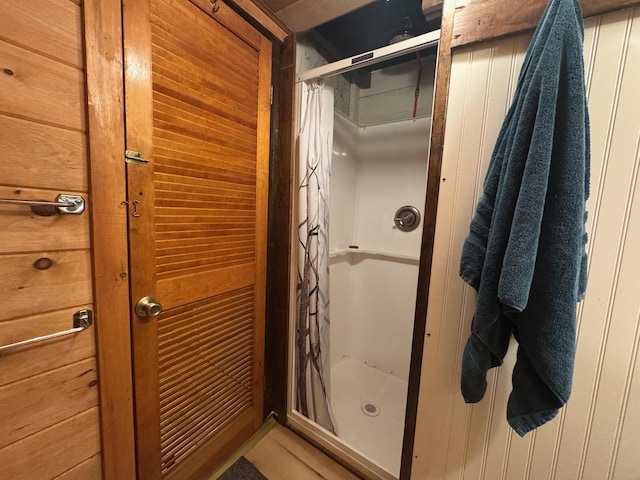 bathroom with wood walls and walk in shower