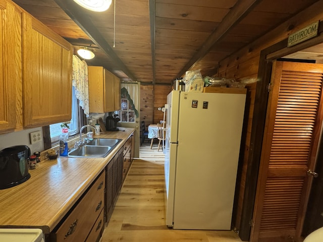 kitchen featuring beamed ceiling, white fridge, wood ceiling, and sink