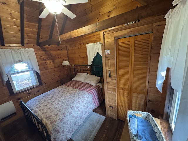 bedroom with ceiling fan, lofted ceiling with beams, dark hardwood / wood-style floors, a closet, and wood walls