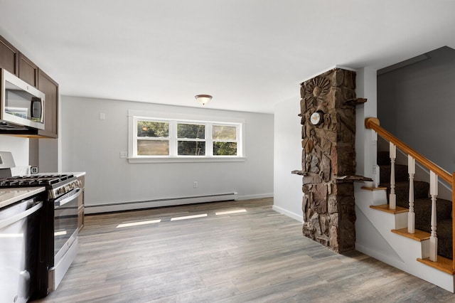 kitchen with appliances with stainless steel finishes, dark brown cabinetry, light hardwood / wood-style floors, and baseboard heating