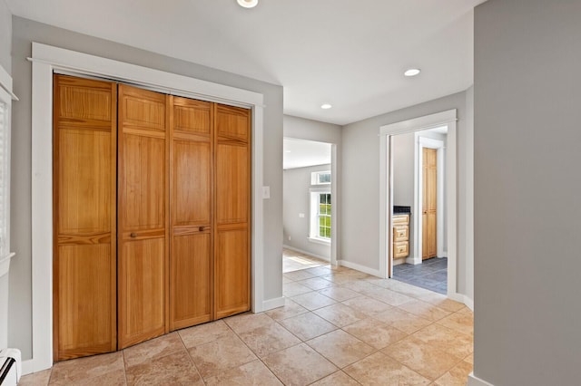 hall with light tile patterned floors and a baseboard heating unit