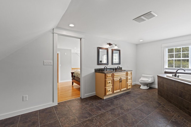 bathroom with vanity, toilet, a bath, and vaulted ceiling