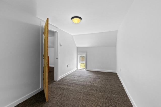 interior space featuring vaulted ceiling and dark colored carpet