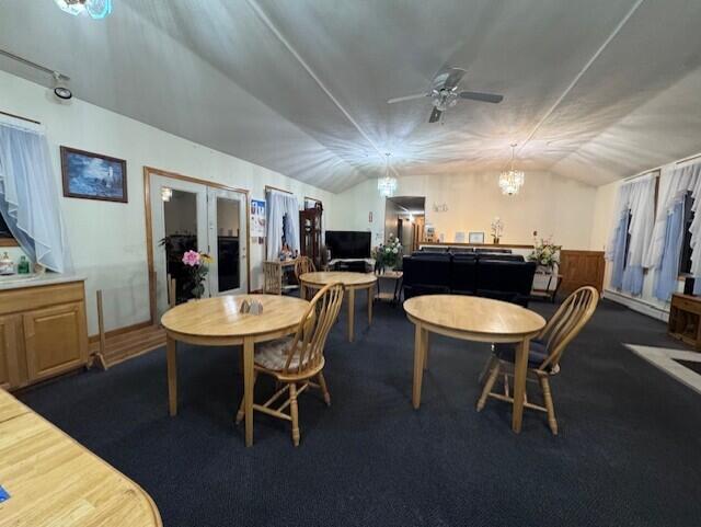 dining area with ceiling fan with notable chandelier and vaulted ceiling