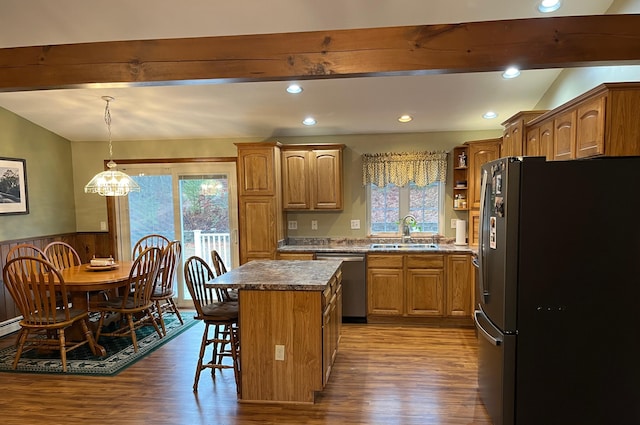 kitchen with stainless steel appliances, sink, decorative light fixtures, a kitchen island, and a breakfast bar area