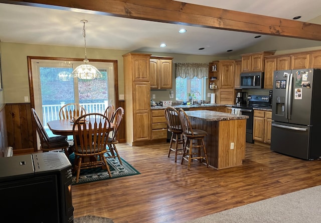 kitchen with a kitchen bar, stainless steel appliances, sink, a kitchen island, and hanging light fixtures