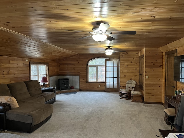 carpeted living room featuring a healthy amount of sunlight, lofted ceiling, a wood stove, and wooden ceiling