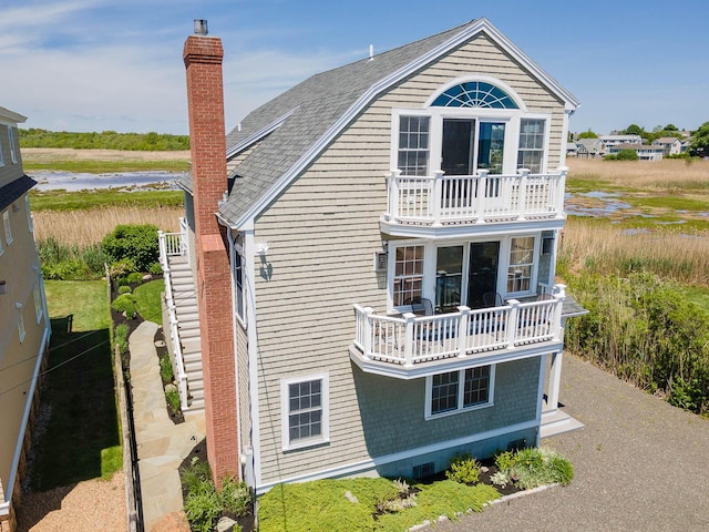 rear view of property featuring a balcony and a water view