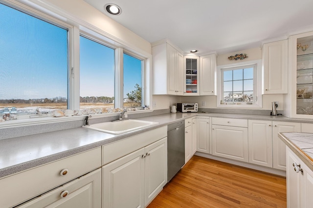 kitchen featuring stainless steel dishwasher, white cabinets, light wood-type flooring, and sink