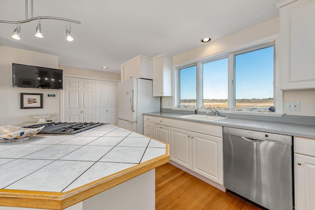 kitchen featuring pendant lighting, tile countertops, white refrigerator, sink, and stainless steel dishwasher