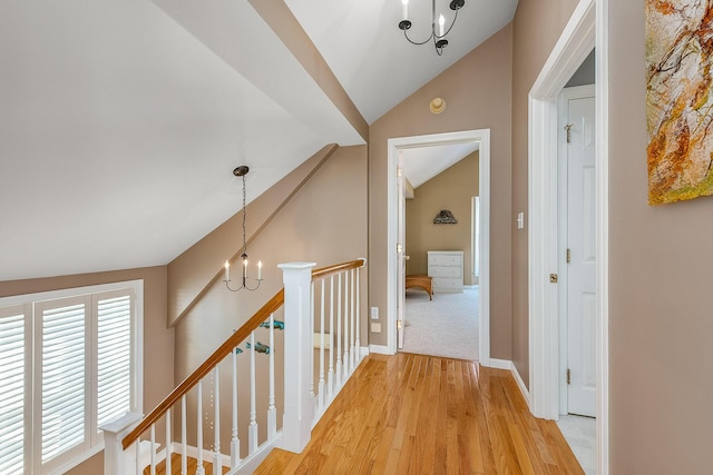 hall with vaulted ceiling, hardwood / wood-style flooring, and an inviting chandelier