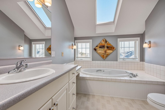 bathroom with lofted ceiling with skylight, a bathtub, vanity, and toilet