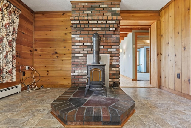 interior details with a textured ceiling, a wood stove, a baseboard heating unit, and wood walls