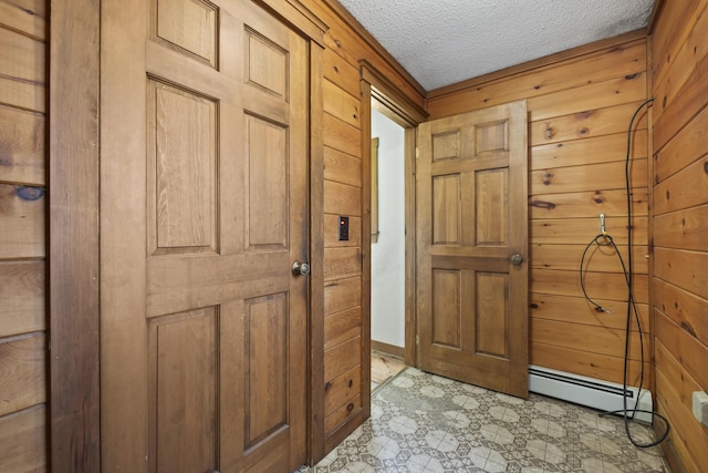 entryway with a baseboard heating unit, a textured ceiling, and wooden walls