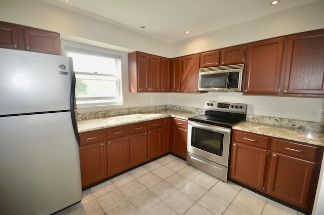 kitchen featuring light stone countertops, light tile patterned floors, and stainless steel appliances