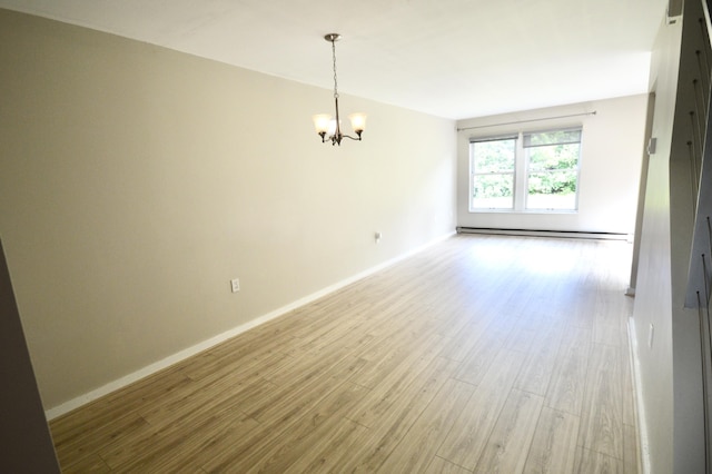 empty room with a notable chandelier, light wood-type flooring, and a baseboard heating unit