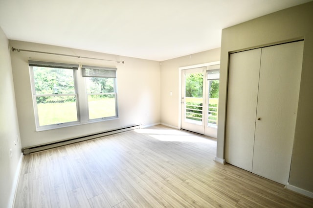 unfurnished bedroom featuring a closet, light hardwood / wood-style flooring, access to outside, and a baseboard radiator