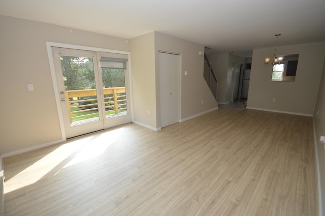 unfurnished living room with light hardwood / wood-style flooring and a chandelier