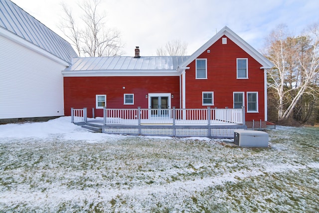 snow covered back of property with a deck