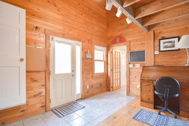 office space with track lighting, light tile patterned flooring, and wooden walls