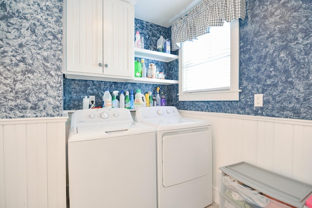 clothes washing area featuring separate washer and dryer and cabinets