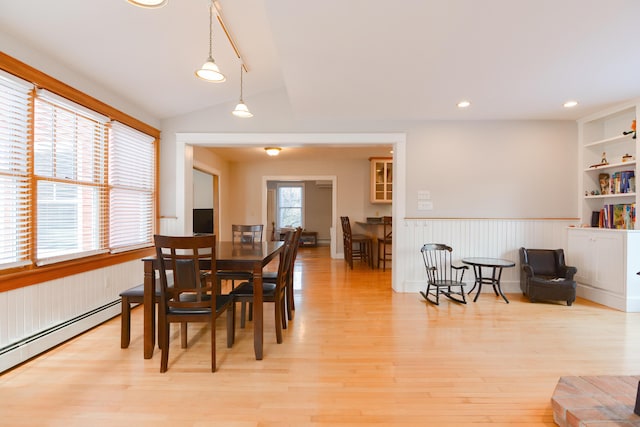 dining space with a baseboard radiator, light wood-type flooring, built in features, and vaulted ceiling