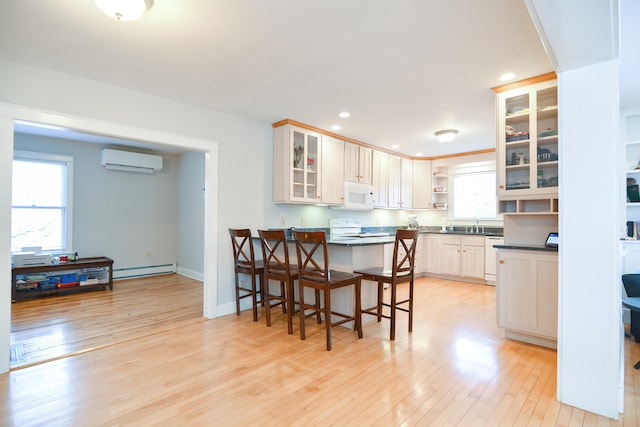 kitchen featuring white appliances, a wall unit AC, light hardwood / wood-style flooring, and a breakfast bar area