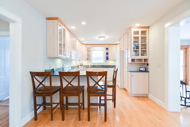 kitchen featuring sink, white cabinetry, white appliances, light wood-type flooring, and kitchen peninsula