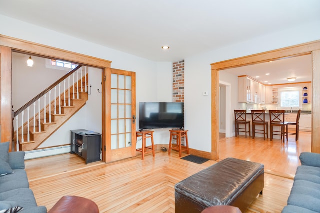 living room with sink, a baseboard radiator, and light wood-type flooring