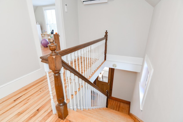 stairway featuring an AC wall unit and hardwood / wood-style flooring