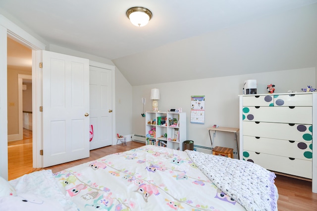 bedroom with lofted ceiling, light wood-type flooring, and a baseboard radiator