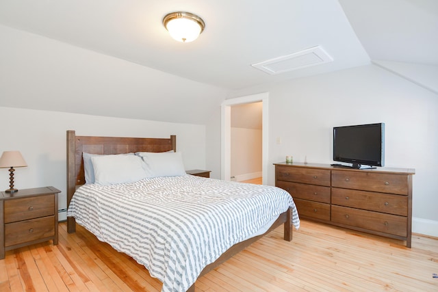 bedroom with light hardwood / wood-style floors, baseboard heating, and vaulted ceiling