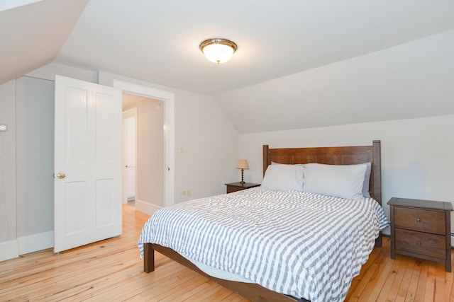 bedroom with light wood-type flooring and vaulted ceiling