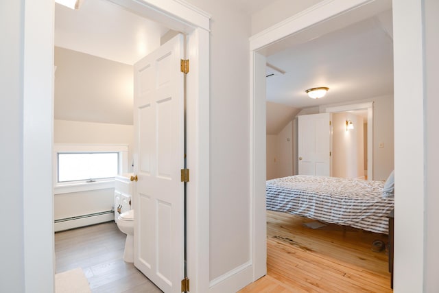 hall featuring lofted ceiling, a baseboard radiator, and light hardwood / wood-style flooring