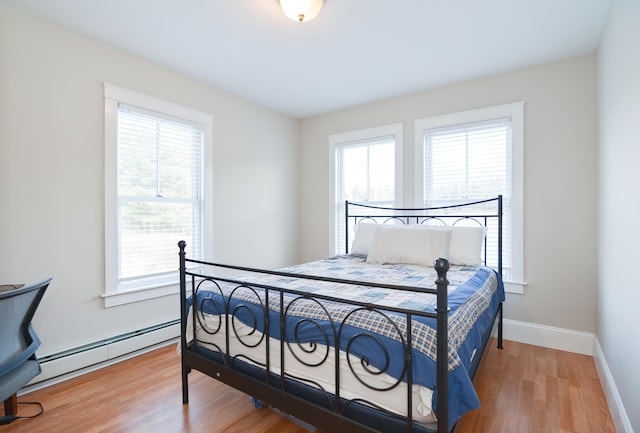 bedroom with baseboard heating and hardwood / wood-style flooring