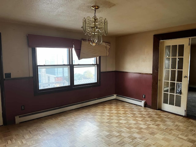 unfurnished dining area featuring a textured ceiling, an inviting chandelier, light parquet floors, and a baseboard heating unit