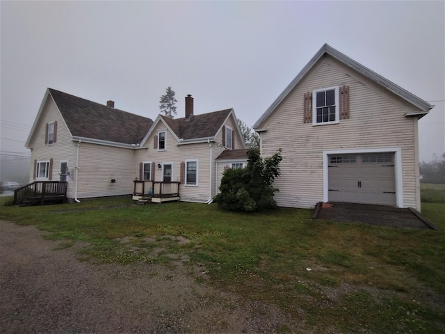 back of house featuring a garage, a yard, and a wooden deck