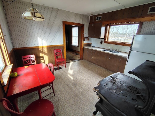 kitchen with pendant lighting, sink, dark brown cabinets, and white refrigerator