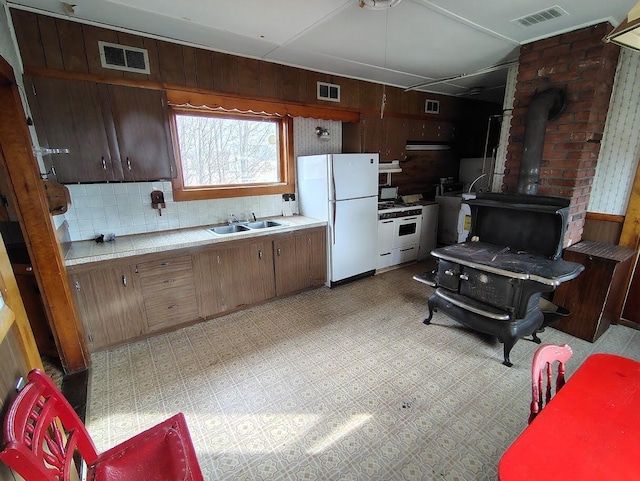 kitchen with a wood stove, sink, and white appliances