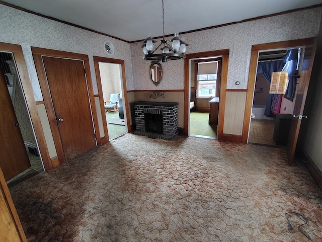 unfurnished living room featuring crown molding, a fireplace, and an inviting chandelier