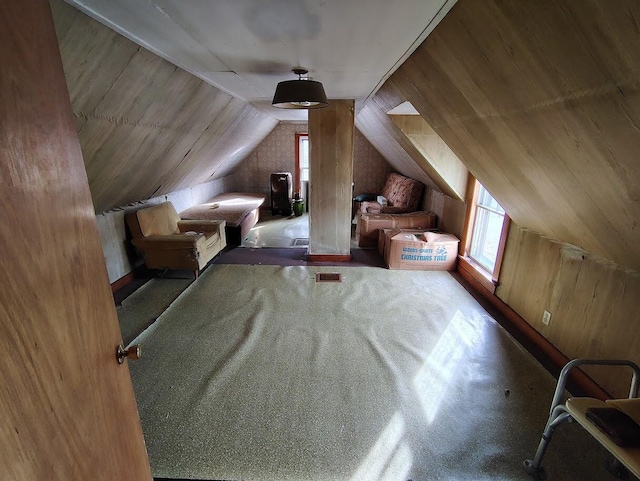 bonus room with lofted ceiling and wooden walls