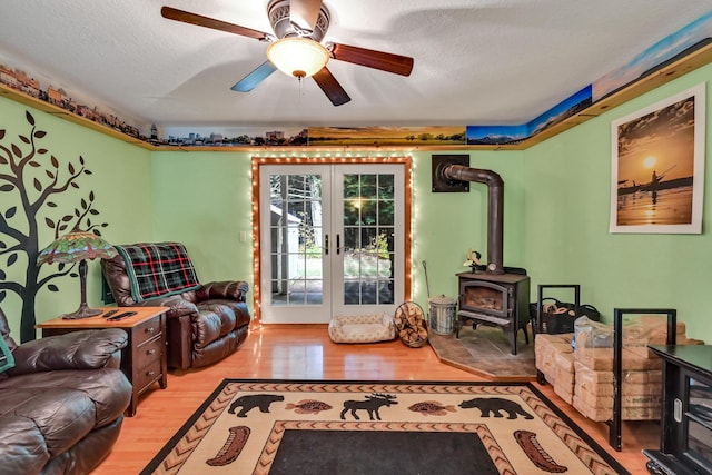 living room with french doors, a textured ceiling, light hardwood / wood-style floors, and a wood stove