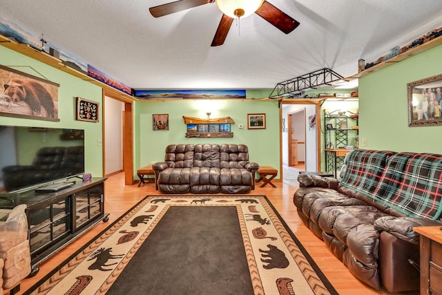 living room with a textured ceiling, light hardwood / wood-style flooring, and ceiling fan