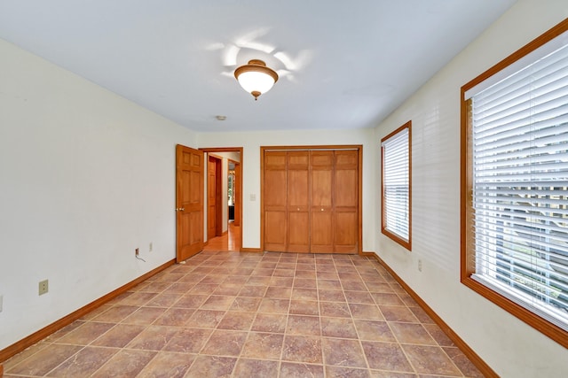 unfurnished bedroom featuring light tile patterned floors, multiple windows, and a closet