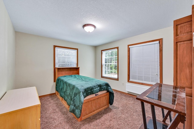 carpeted bedroom featuring radiator heating unit and a textured ceiling